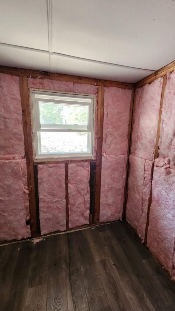Basement room with pink insulation installed between the wall studs