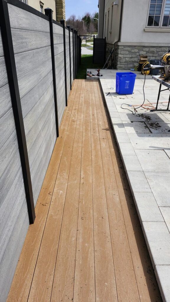 Composite deck boards alongside a grey composite privacy fence