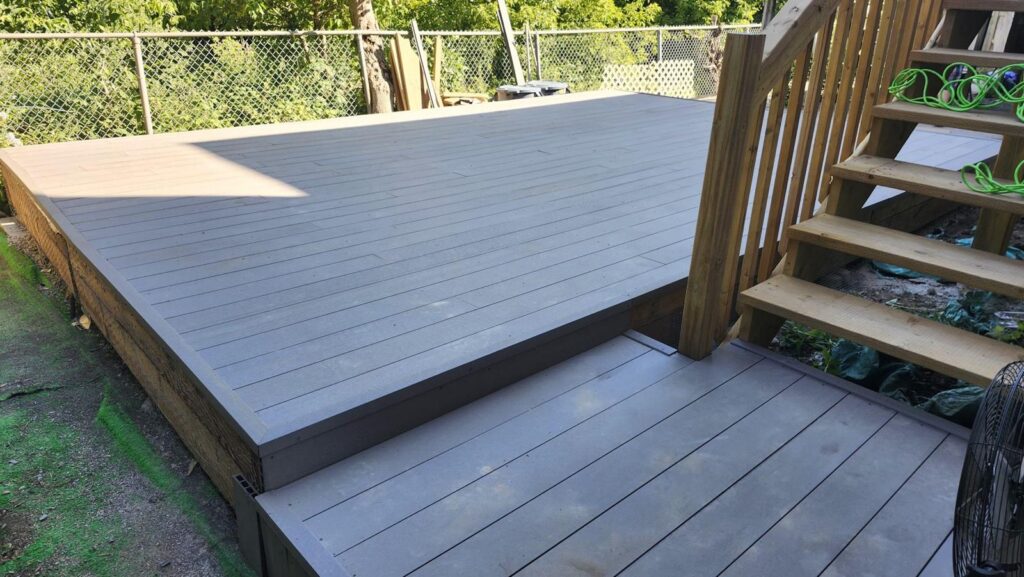 Grey composite deck with wooden stairs and railing