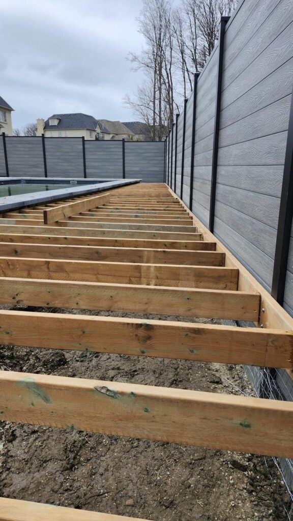 Pressure-treated deck framing next to a composite privacy fence