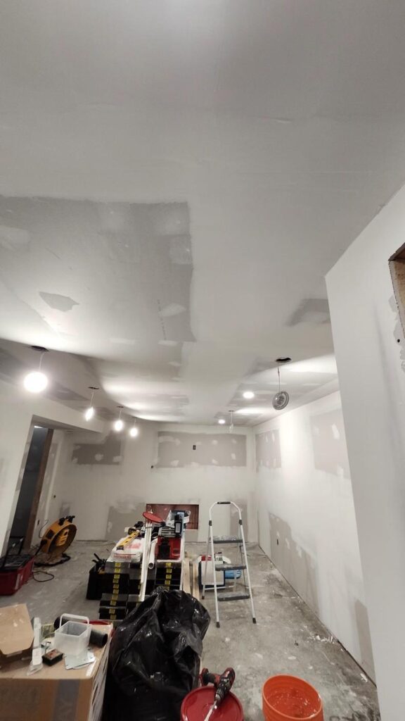 Open basement area with drywall installed and joint compound applied